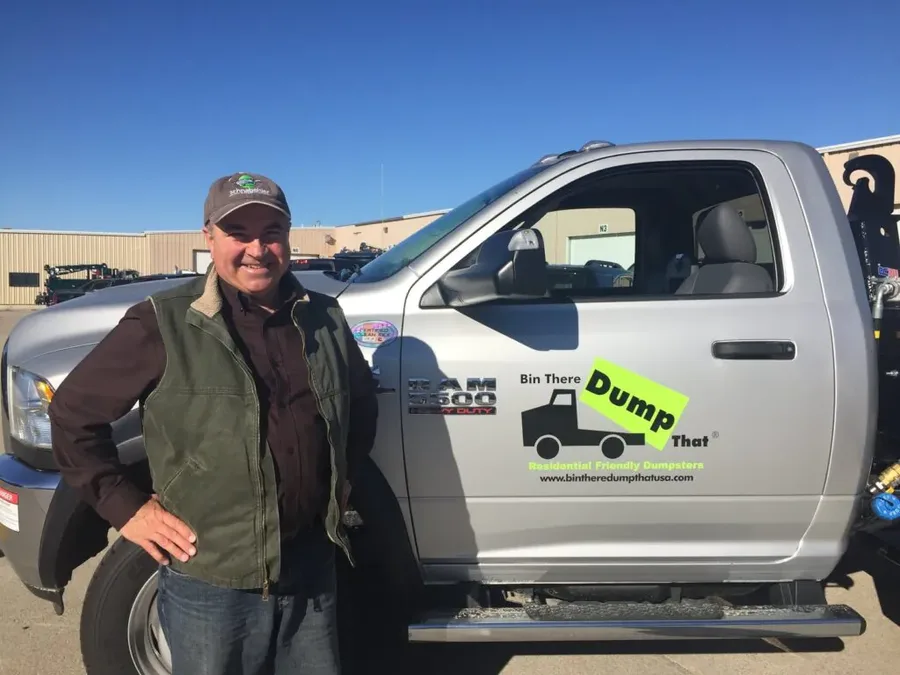 Ron Lee, owner of Bin There Dump That, standing next to a dumpster delivery truck